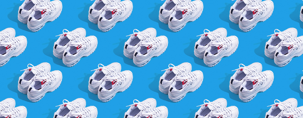 pairs of white athletic sneakers resting against a blue background