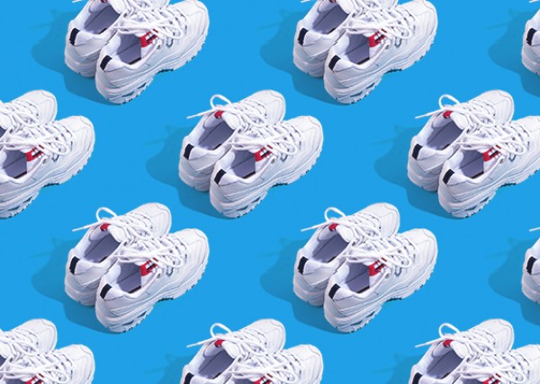 pairs of white athletic sneakers resting against a blue background