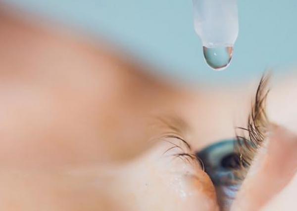 closeup of a person putting an eye drop in their eye